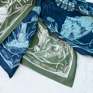 Green and blue bandanas with nature-themed designs on a white surface.