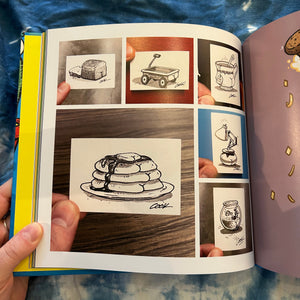 Open book with illustrations of food items with butts held by a person.