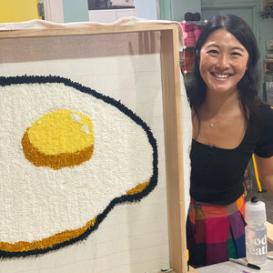 Woman standing next to tufted artwork of a fried egg.