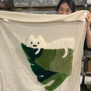 Person holding a tufted art piece with a cat design.