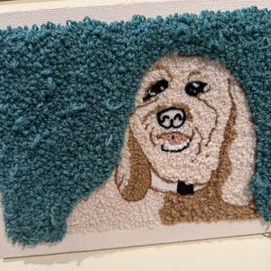 Punch needle wall hanging a dog design on a plain background.