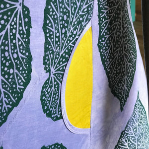 Close-up of pocket detail with green leaf pattern and yellow center on a light blue background.