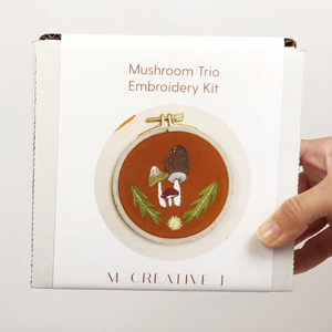 Mushroom Trio Embroidery Kit held by a hand on a light gray background.