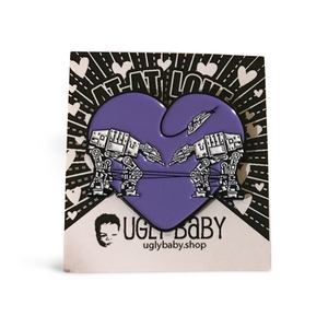 Heart shaped enamel pin called Love AT-AT First Sight with a purple background. Shown on a square paper background with black and white hearts.