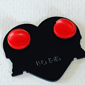 The back of a heart-shaped pin with two red circular rubber backers and the embossed text 'UGLY BABY' on a white background.