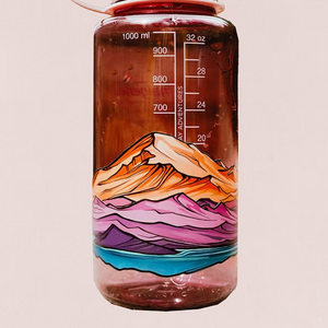 Water bottle with infininty sticker of Mount Baker and Twin Sisters mountain design and white lid on a beige background. The sticker wraps around the bottle multple times to create a layered landscape.