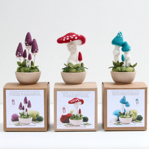 Three different needle felted mushroom kits shown in this photo displayed sitting on top of their retail packaging.