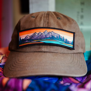 Brown cap with a mountain patch on a tan fabric background