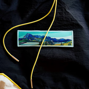 Embroidered patch of a mountain landscape on a black fabric background