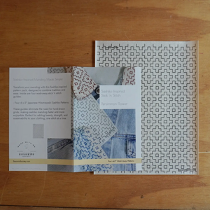 Patterned fabric and Sashiko pattern booklets on a wooden surface.