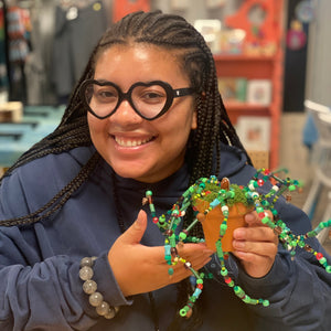 Person holding a beaded plant creation in a store setting.