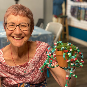 Woman holding a beaded plant in an indoor setting.