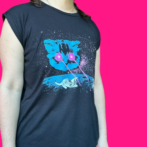 A person wearing a dark navy sleeveless t-shirt with a graphic print of a blue cat's face, white cats, and pink laser beams on a starry black background, set against a solid bright pink backdrop.