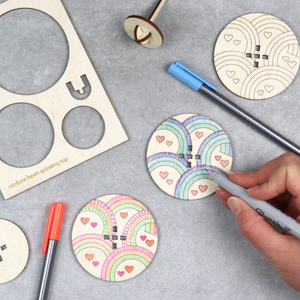 Hand coloring circular wooden cutouts with markers to create a spinning top.