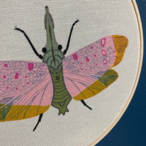 Embroidery hoop with a colorful moth design on fabric
