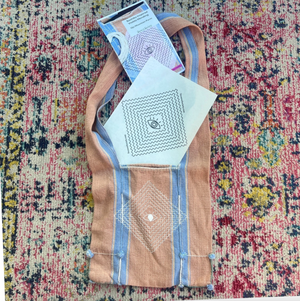 Brown fabric bag with geometric patterns on a colorful textured surface.