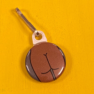 Small round zipper pull with a flat butt featured on a yellow surface.