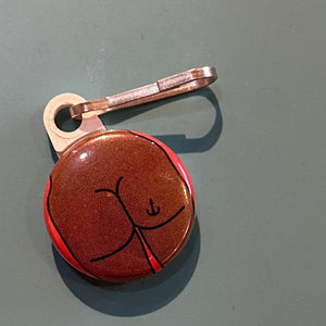 Zipper pull with a square butt with an anchor tattoo on a gray background.
