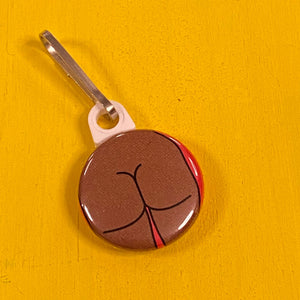 Round zipper pull with a square butt on a yellow surface.