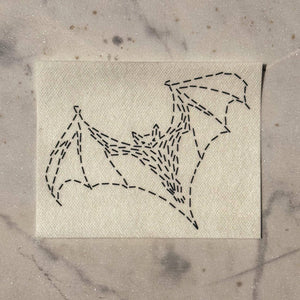 Visible mending pattern of a bat in flight against a marble background