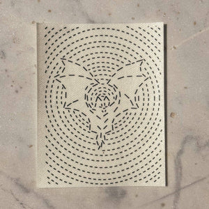 A visible mending patch of a bat in flight surrounded by concentric circles on a marble background.