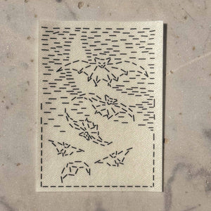 A visible mending guide sticker featuring a design of six bats and hatched lines that create the silhouette of a crescent moon.