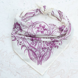 White scarf with purple floral pattern on a textured white background.