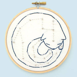 Embroidery hoop with a cat silhouette and star pattern on a light blue background