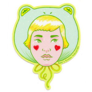 Sticker with a stylized face design wearing a frog hat on a white background