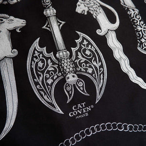 Decorative design on a bandana with a dagger, axe, and other elements on a black background with 'Cat Coven' branding.