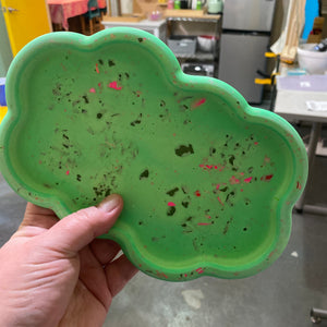 Green textured plate held by a hand in an indoor setting.