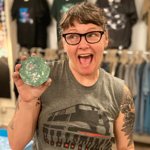 Person holding a green coaster in a store setting.