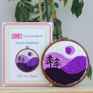 Punch needle kit with completed project and packaging on a wooden surface with plants in the background