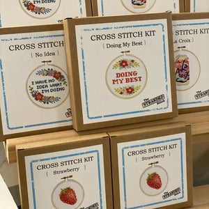 Cross stitch kits with embroidered designs in cardboard boxes. Included are: I have no idea what I'm doing, Doing my best, La Croix and mini Strawberry.
