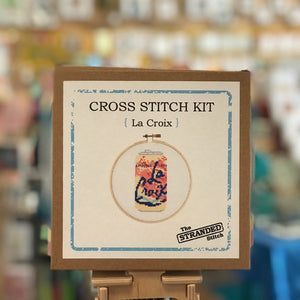 Package for Stranded Stitch La Croix Cross Stitch Kit. It is a kraft colored box with a white sticker that has a photo of a completed project.