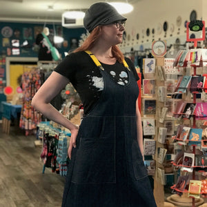Person wearing a dark blue apron dress in a store setting.