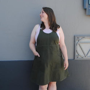 Woman wearing a green dress standing against a gray wall.