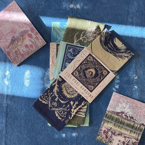 Collection of greeting cards and bandanas on a textured blue surface.