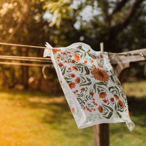 A floral patterned bandana hanging on a clothesline in an outdoor setting.