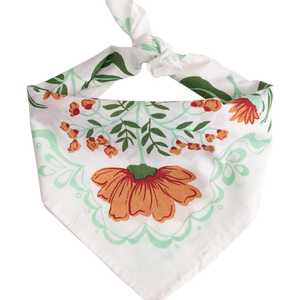 White bandana with a orange and green floral pattern tied into a scarf