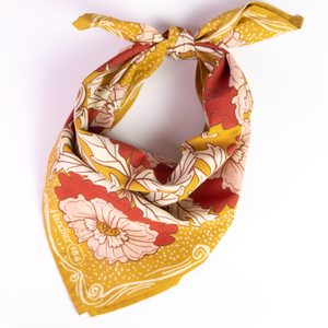 A yellow floral patterned bandana tied into a scarf, against a white background.