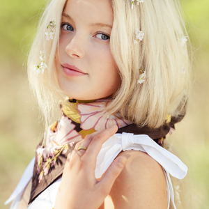 Woman with flowers in her blonde hair modeling a floral patterned bandana as a neck scarf.