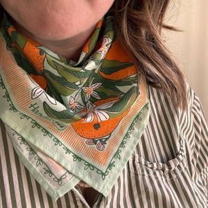A person wearing a patterned bandana as a neck scarf.