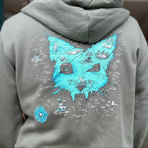 Person standing with their back to us. On the back of their army green hoodie is our Catographer print. It is an island in the shape of a cat head.