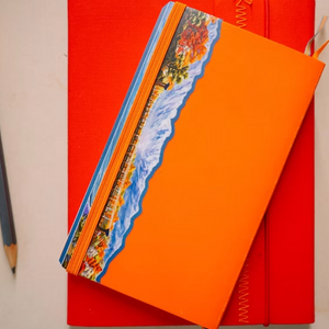 An orange notebook with the kamikochi miniscape sticker on it