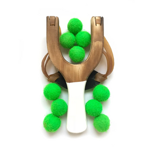 Wooden slingshot with green balls on a white background