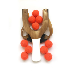 Wooden slingshot with neon orange felt balls on a white background