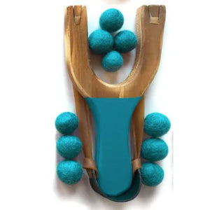 Wooden slingshot with teal felt balls on a white background