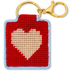 Needlepoint keychain featuring a pink heart on a red background with a blue border and gold hardware.