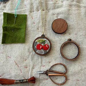 Handmade jewelry set with pendants, scissors, and embroidery tools on fabric background
